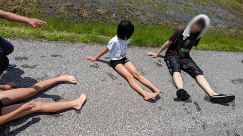 田んぼで泥あそびで疲れた体を休める子供たち