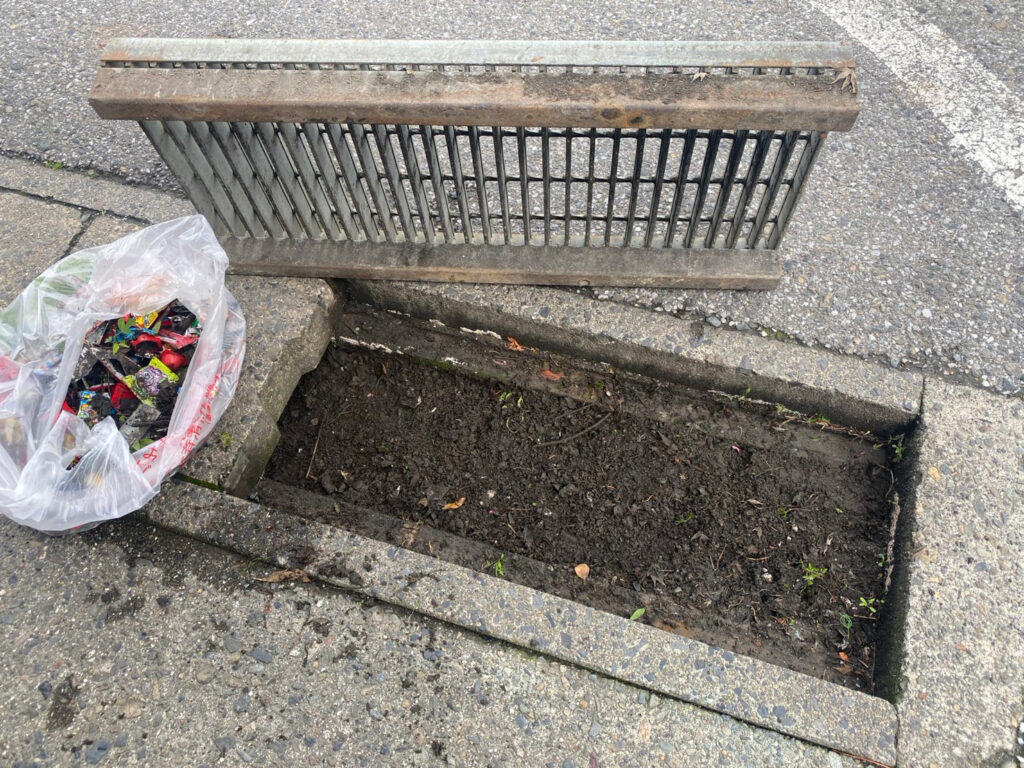 側溝に違法に捨てられたお菓子のゴミを回収した後の画像