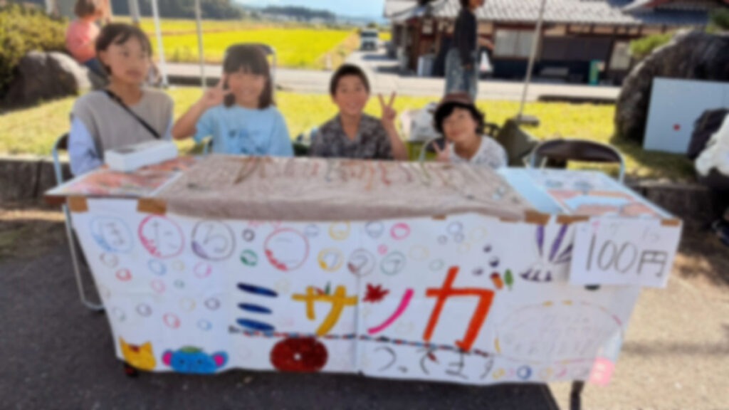 学童の子ども達が作ったミサンガの販売ブースでピースをする子ども達